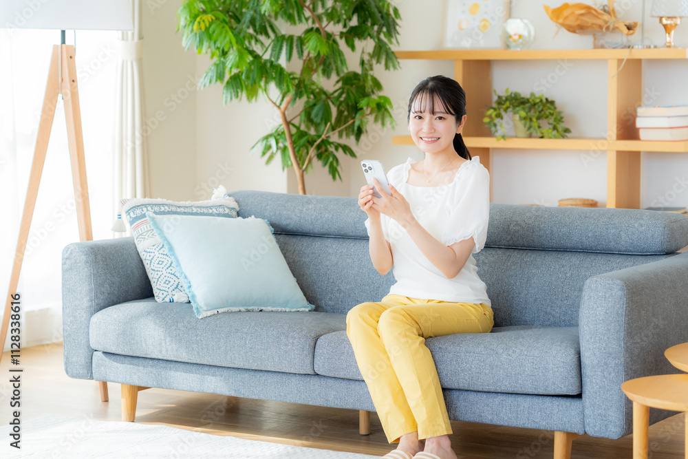 部屋でスマホを操作する若い女性 部屋でスマホを操作する若い女性