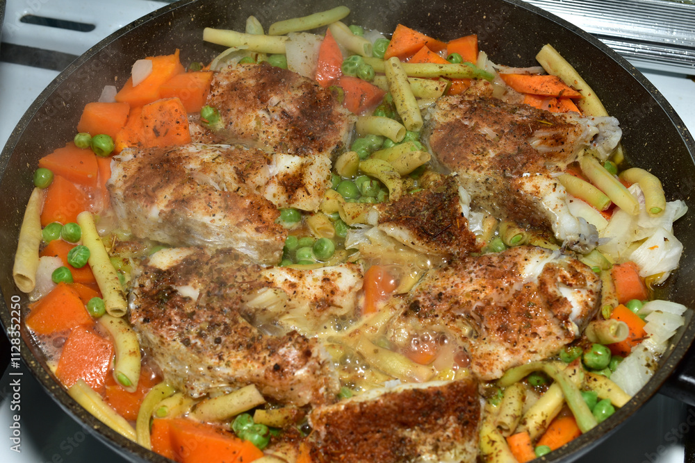 Cod cut into pieces is cooked in a frying pan together with vegetables. Cod cut into pieces is cooked in a frying pan together with vegetables.