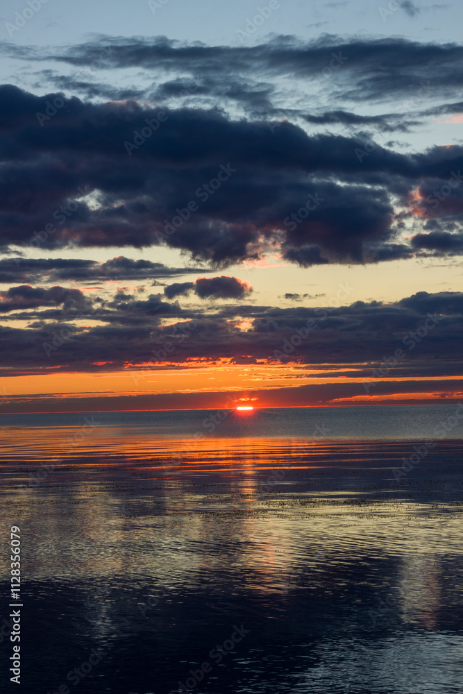 Obraz premium Orange sunrise with dark clouds on the shore. Lake Ladoga.