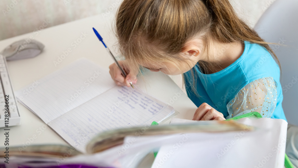 Little school girl sit at table at home write in exercise book prepare homework alone. Little school girl sit at table at home write in exercise book prepare homework alone.
