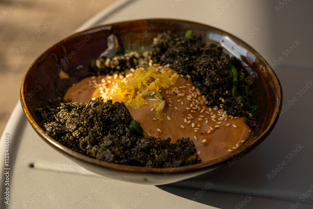 Vegetarian spinach salad closeup. Fried spinach with nori and tahini, vegan dish in sunlight Vegetarian spinach salad closeup. Fried spinach with nori and tahini, vegan dish in sunlight