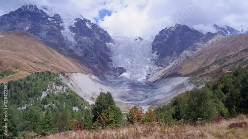 Pan across toe of Adishi Glacier in Caucasus Mtns from highland meadow photo