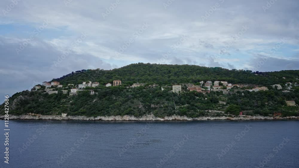 Coastal hillside view with lush greenery and cliffside homes under a cloudy sky offering a scenic panorama. Coastal hillside view with lush greenery and cliffside homes under a cloudy sky offering a scenic panorama.