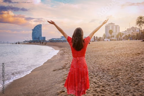 A happy tourist woman enjoys the sunset at the Beach of Barcelona, Spain photo