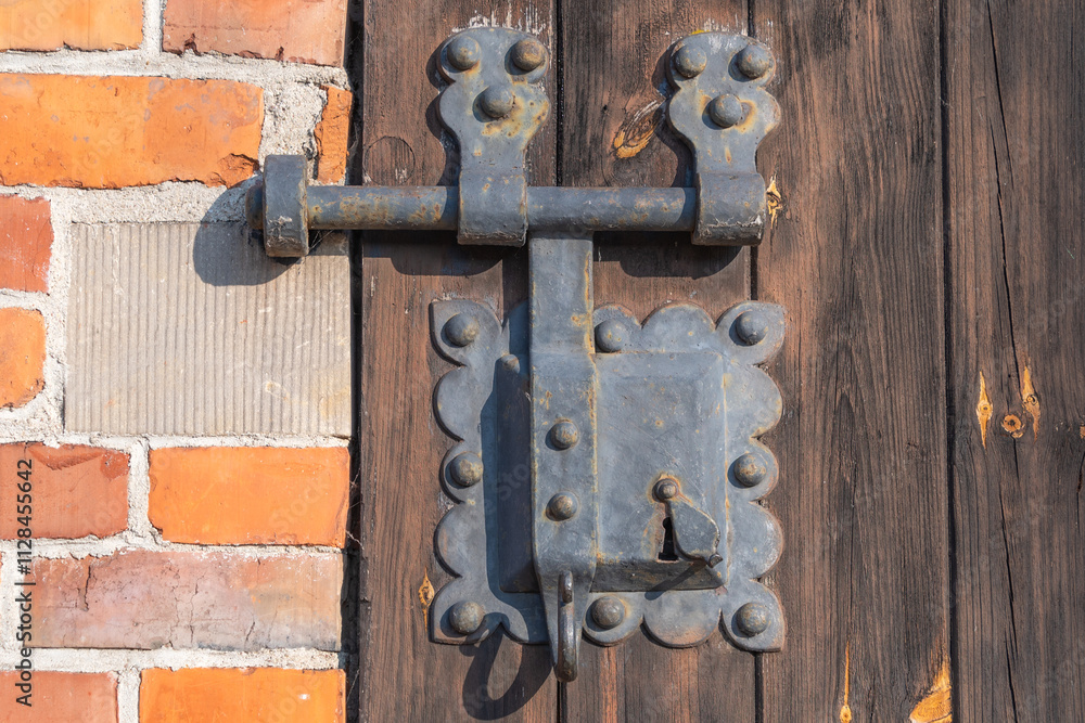 a rustic door lock featuring an ornate, weathered metal design attached to a wooden door a rustic door lock featuring an ornate, weathered metal design attached to a wooden door