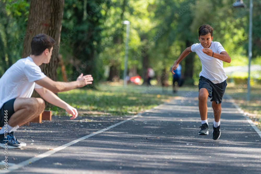 Fototapeta premium Trainer works with a boy to improve speed and running technique in the park. Focused on building agility and endurance, the outdoor training session promotes healthy physical activity for kids.