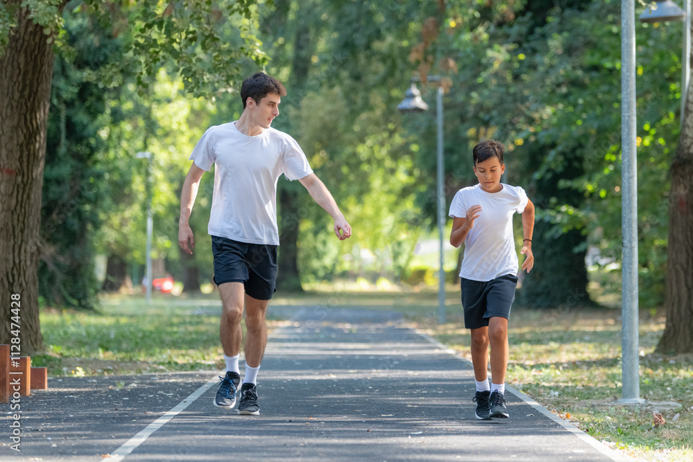 Fototapeta premium Trainer runs alongside two boys in a sunny park, focusing on improving their endurance and physical fitness. The boys are energized, learning proper running techniques while enjoying outdoor exercise