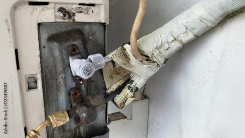 The piping in the outdoor AC unit is frozen and covered with a layer of frost, indicating that the refrigerant level in the AC is low or there is a leak.