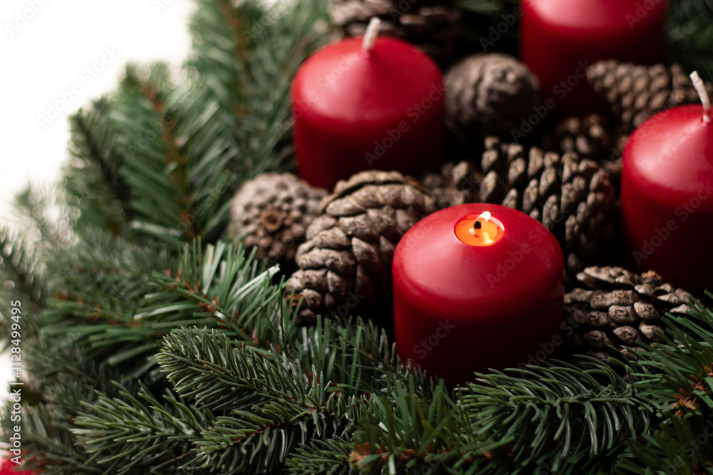 Close up of an advent wreath with one red burning candle on white table Close up of an advent wreath with one red burning candle on white table