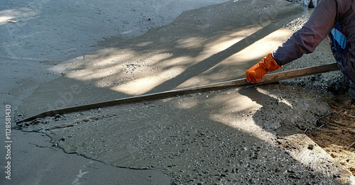 Construction worker levelling a newly poured concrete floor at a farm in Central Thailand
