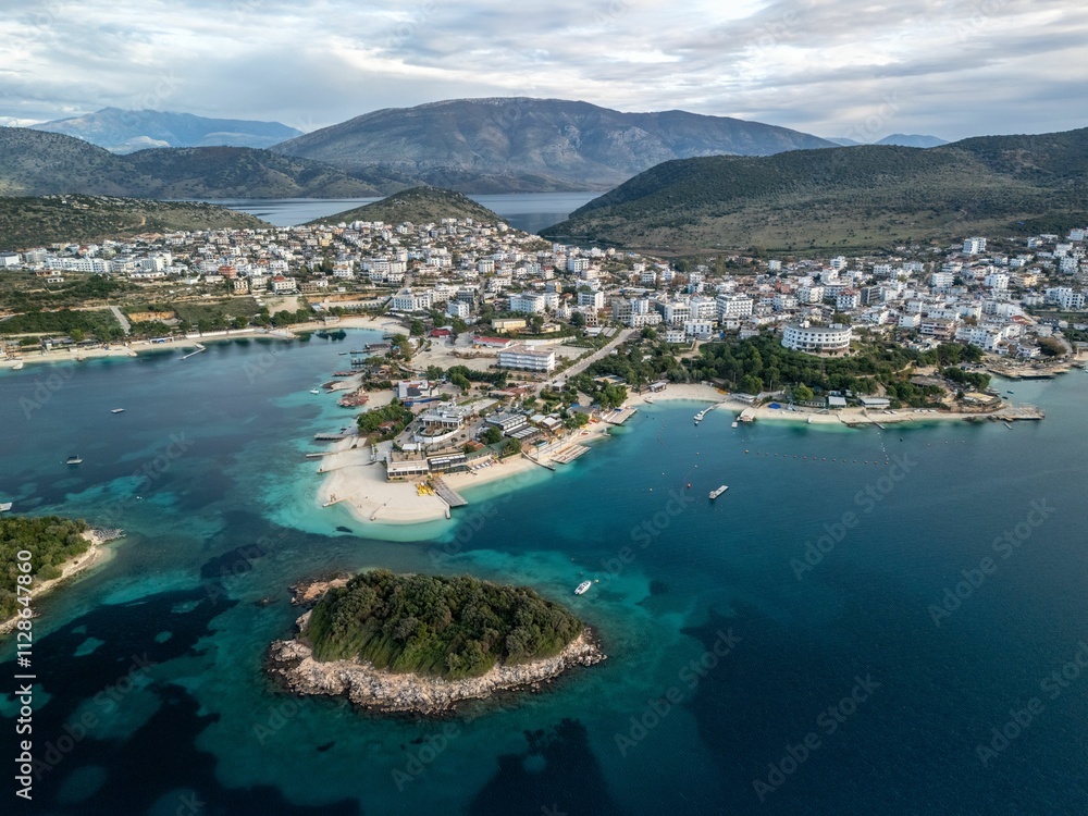 Naklejka premium Aerial view of Ksamil resort village surrounded by blue waters and majestic mountains. Albania