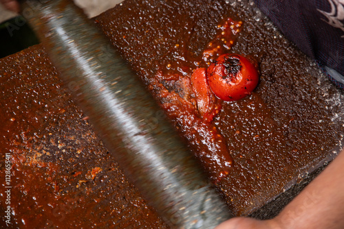 Woman from an indigenous community in Oaxaca preparing traditional Mole Rojo with a metate, a tool for grinding ingredients in Mexico. photo