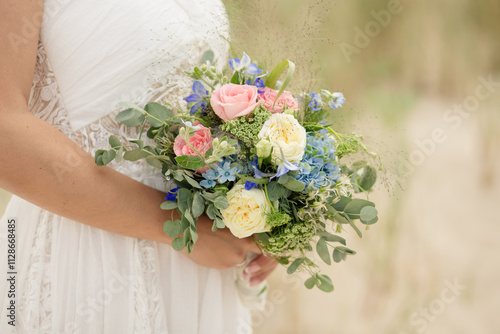 Braut mit romantischem Blumenstrauß in Pastelltönen am Strand photo