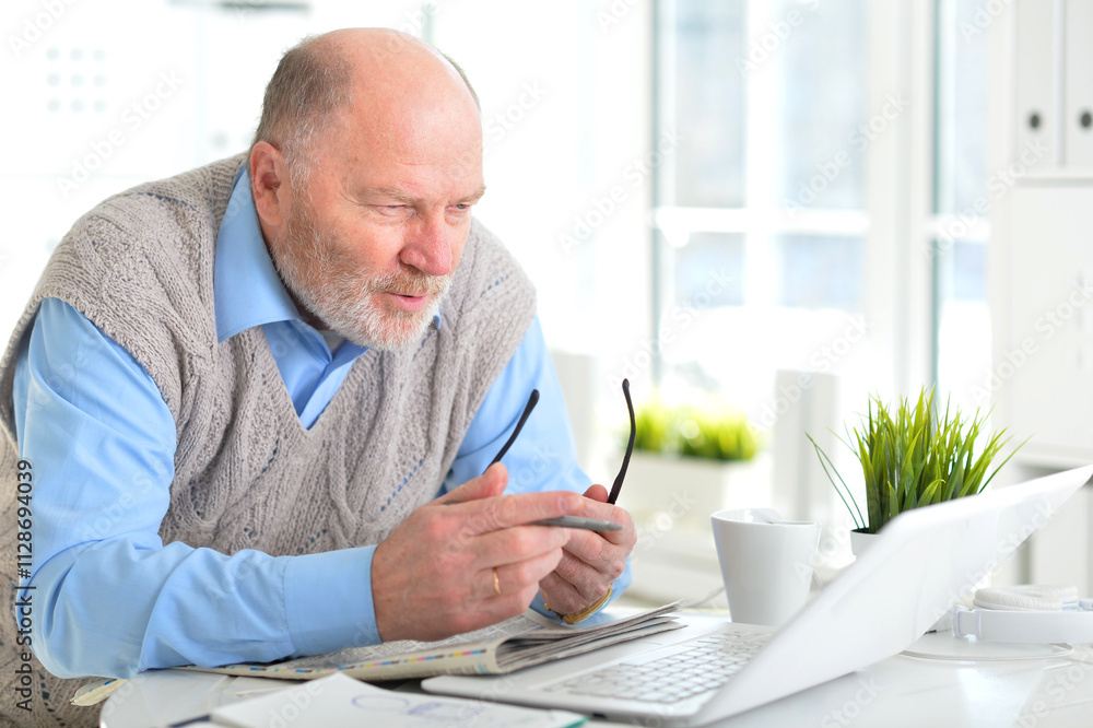 Portrait of an elderly man using a laptop in an office Portrait of an elderly man using a laptop in an office