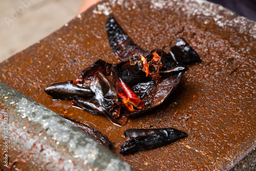 Preparing Mexican Mole Negro. Oaxaca chiles have to be cleaned, toasted on a comal over a flame and soaked in water before grinding with metate. photo