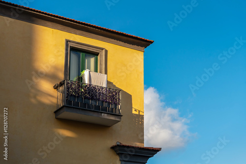 Obraz na płótnie Fragment of a yellow Italian house with a balcony against a blue sky w salonie