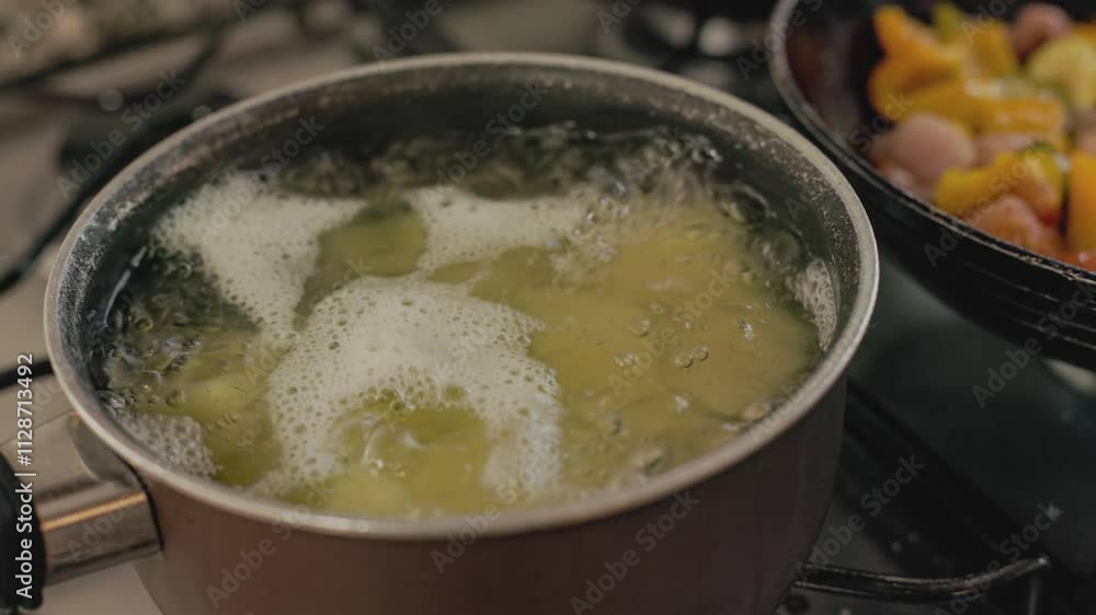 Water boiling in pot on stove with vegetables cooking Water boiling in pot on stove with vegetables cooking