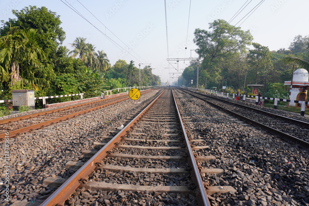 The railway track surrounded with green trees in West Bengal, India The railway track surrounded with green trees in West Bengal, India