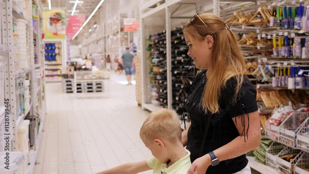 Close-up of a woman with a child in a hypermarket, standing in front of the counters, they choose plastic dishes. Close-up of a woman with a child in a hypermarket, standing in front of the counters, they choose plastic dishes.