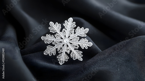 A close-up of a single intricate snowflake resting on a piece of black fabric. photo