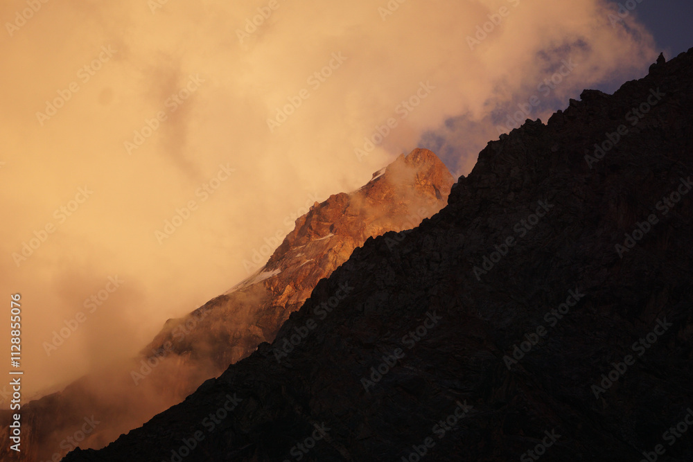 Mountain rock peaks are shrouded in clouds during sunset Mountain rock peaks are shrouded in clouds during sunset