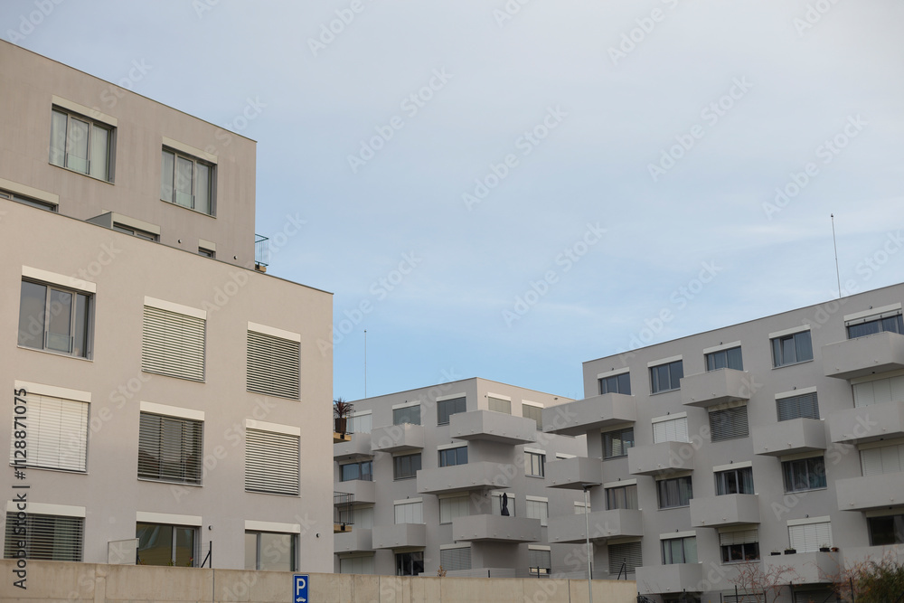 A long row of apartment buildings adorned with balconies, all set against the backdrop of a cloudy sky on a somewhat overcast day A long row of apartment buildings adorned with balconies, all set against the backdrop of a cloudy sky on a somewhat overcast day