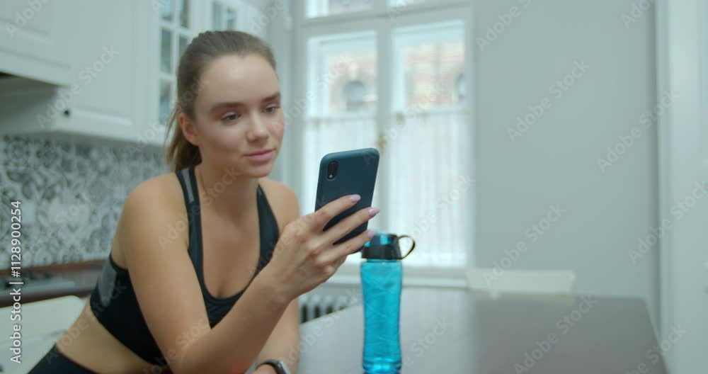 Woman uses the smartphone while relaxing after training at home. Training on distance. Woman uses the smartphone while relaxing after training at home. Training on distance.
