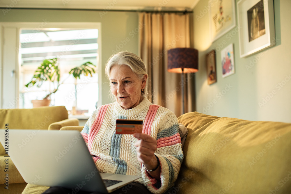 Smiling senior woman online shopping with credit card and laptop at home Smiling senior woman online shopping with credit card and laptop at home