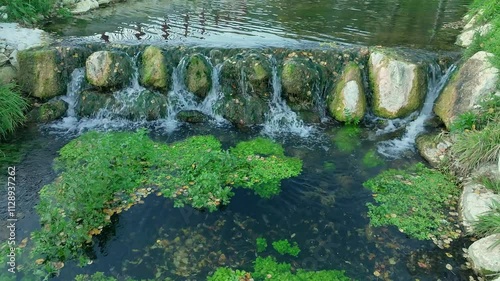 CLEAR WATER FLOWING OVER THE STONES OF A SMALL WATERFALL 4