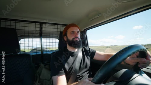 Focused man with beard drives car along road in countryside