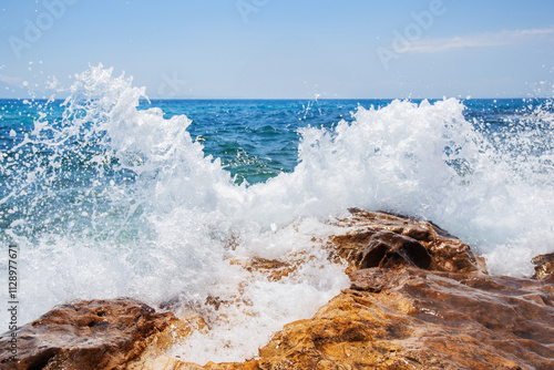 Dynamic Ocean Waves Splash Over Rugged Rocks, Creating A Refreshing Coastal Seascape Under Clear Skies photo