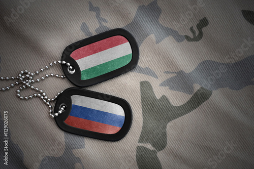 vintage army blank, dog tag with flag of hungary and russia on the khaki texture background. military concept. photo