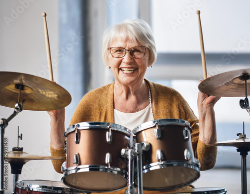 senior woman learning to play the drums at her home