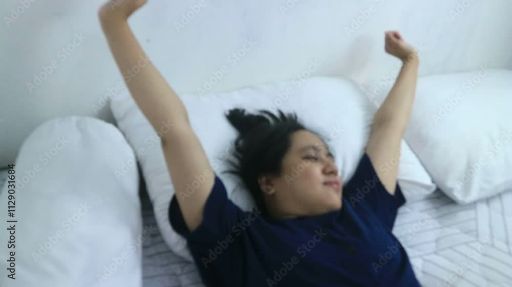 Smiling asian woman in pajama stretching in bed after wake up Smiling asian woman in pajama stretching in bed after wake up