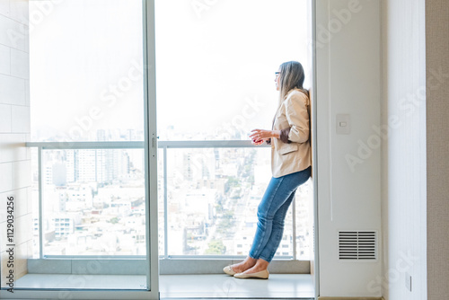 A woman is standing on a balcony looking out at the city