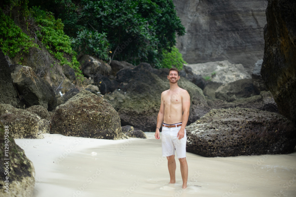 A person enjoying a secluded beach surrounded by lush greenery and rocky cliffs. A person enjoying a secluded beach surrounded by lush greenery and rocky cliffs.