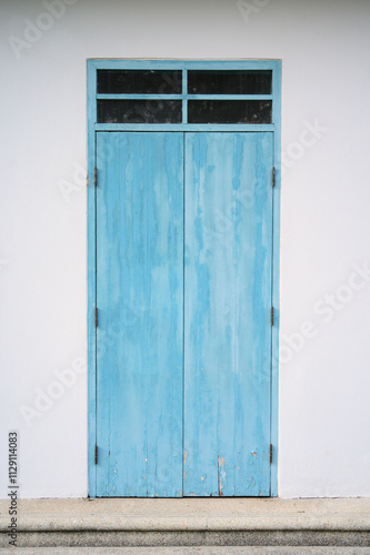 Blue old and deteriorated door with glass window