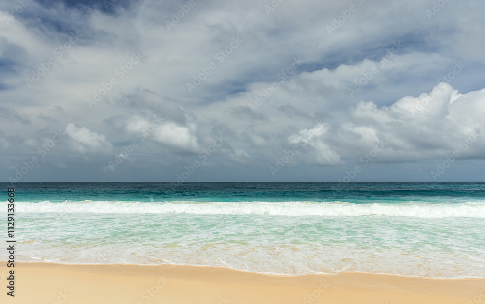 Shore waves and white sand are under dramatic dark cloudy sky Shore waves and white sand are under dramatic dark cloudy sky