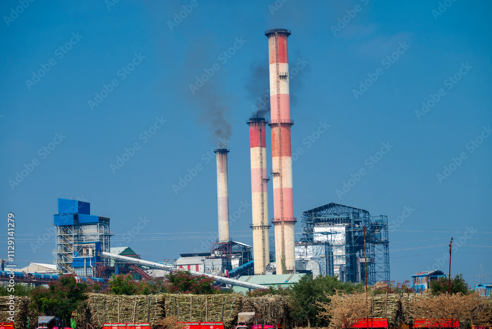 Obraz premium sugar mill, sugar factory in India, A sugar cane mill is a factory that processes sugar cane to produce raw sugar or plantation white sugar. Increasing air pollution to factory smoke.