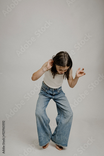 Dunkelhaariges Mädchen, 10, in Blue Jeans, macht einen lustigen Move photo