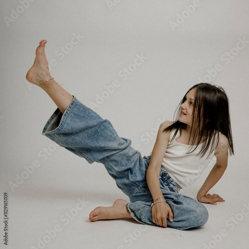 Dunkelhaariges Mädchen, 10, in Blue Jeans, turnt am Boden photo