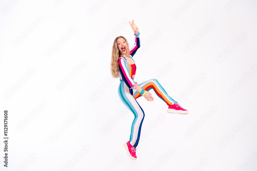 Energetic young woman in a colorful striped outfit jumping joyfully against a white background.