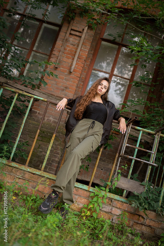 Beautiful young woman posing outdoors near an old brick building..