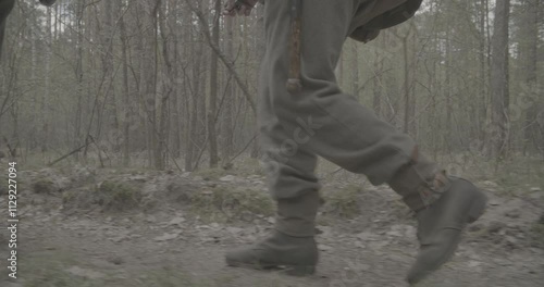 Group Of Reenactors Dressed As German Infantry Soldiers Marching By Forest Autumn Season. Close-up View Of Feet Of Marching Soldiers. Wermacht German Uniform During Ww2. Infantry Military Campaign photo