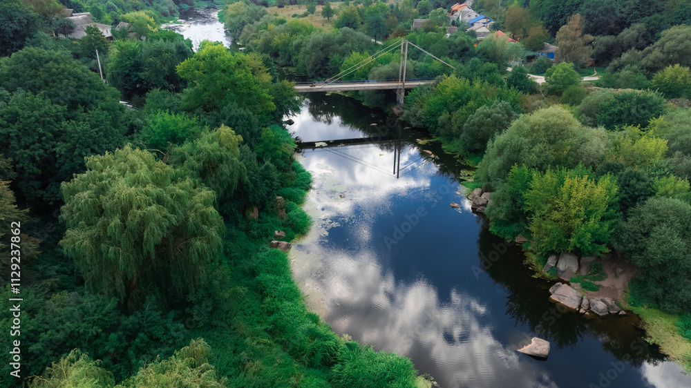 aerial outskirts suburban country side land view with trees foliage top and river water stream with bridge along rustic settlement village Eastern European aerial outskirts suburban country side land view with trees foliage top and river water stream with bridge along rustic settlement village Eastern European