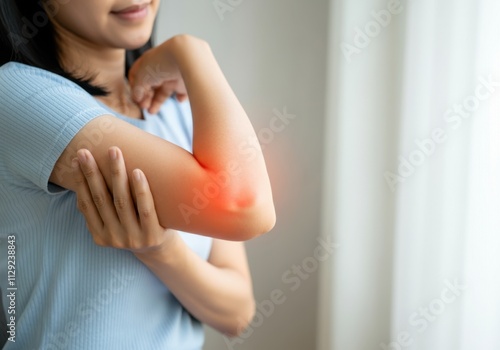 Young woman holding her elbow, highlighted in red, indicating pain and discomfort photo