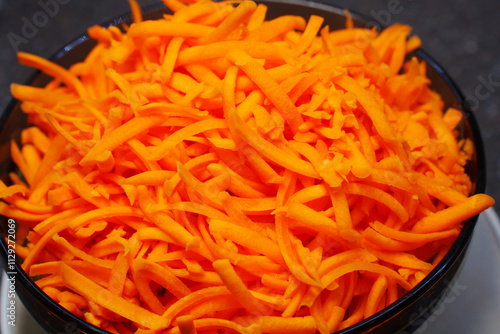 a large bowl of grated carrots. Cooking a vegetable salad from fresh vegetables. all-purpose grater.