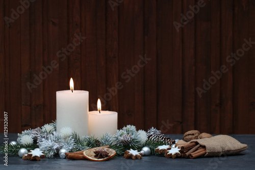 Weihnachtshintergrund: Weiße Kerzen mit Weihnachtsschmuck, Äpfeln, Zimtsternen und Tannenzweigen vor einem Holzhintergrund mit Platz für Text. photo