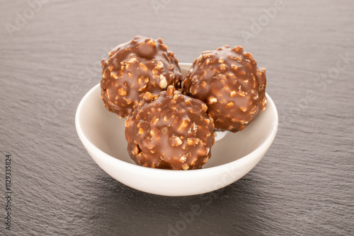 Foto Chocolate candies with hazelnuts on slate stone, close-up.