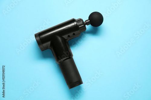 One black percussive massager on light blue background, top view